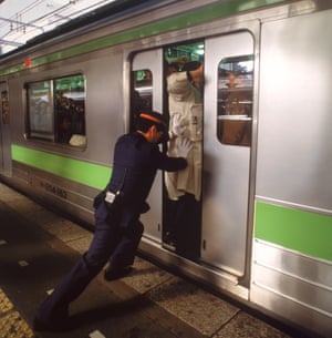 A ‘pusher’ squeezes people on to a Tokyo metro train.