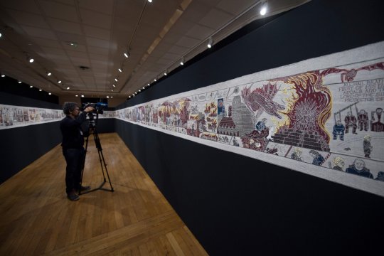 A journalist films a section of a 87 meters tapestry relating the 8 seasons of US television series "Game of Thrones" on September 13, 2019 in Bayeux. - Like the Bayeux Tapestry, the Game of Thrones Tapestry is woven of fine linen and hand-embroidered, with decorative borders and a central pictorial narrative. (Photo by LOIC VENANCE / AFP)LOIC VENANCE/AFP/Getty Images