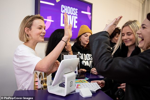 Celebration: Carey handed out high-fives as she served customers in the Choose Love store on Friday