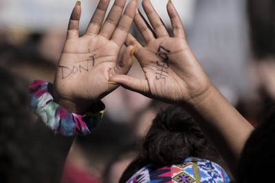A student whose hands read “don&#x27;t shoot” holds her hands in the air during a 2018 high school walkout.