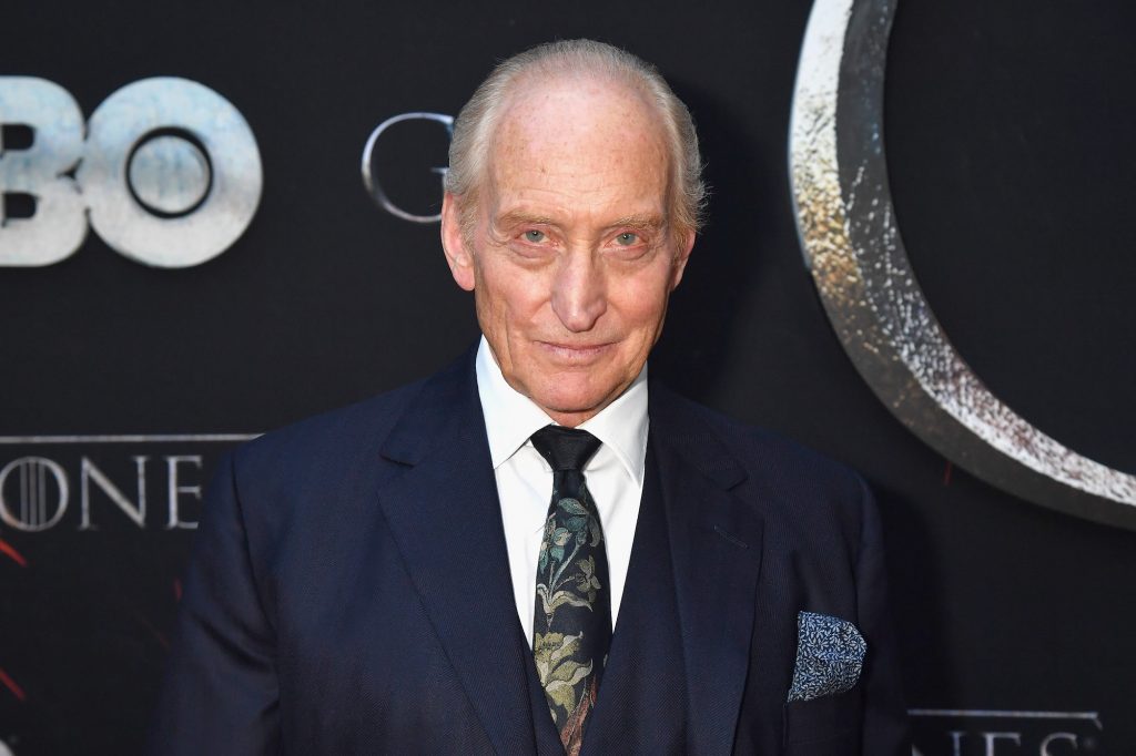 Charles Dance smiling in front of a black background