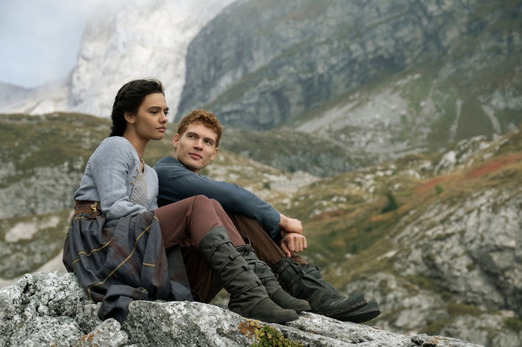 Egwene  (Madeleine Madden) and Rand (Joshua Stradowski) share a quiet moment sitting outside among rocks and grass in "The Wheel of Time." 