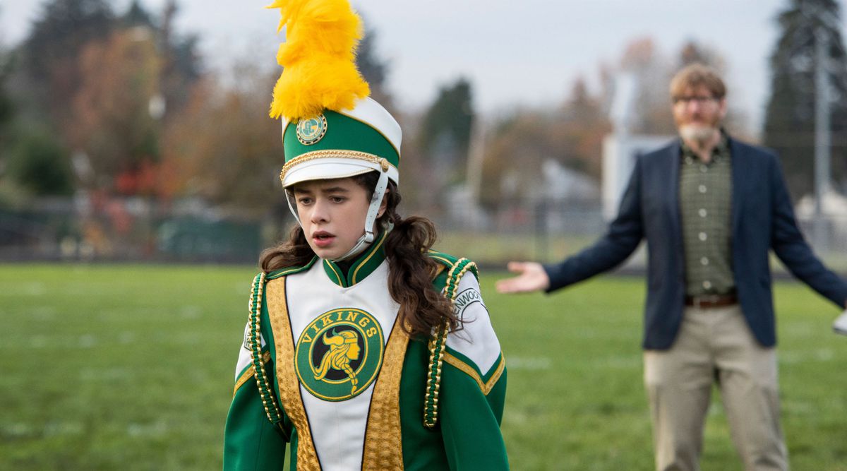 Emily (Isis Hainsworth), in full green, white, and gold marching-band regalia, storms off the field and leaves Chuck Klosterman behind in Metal Lords