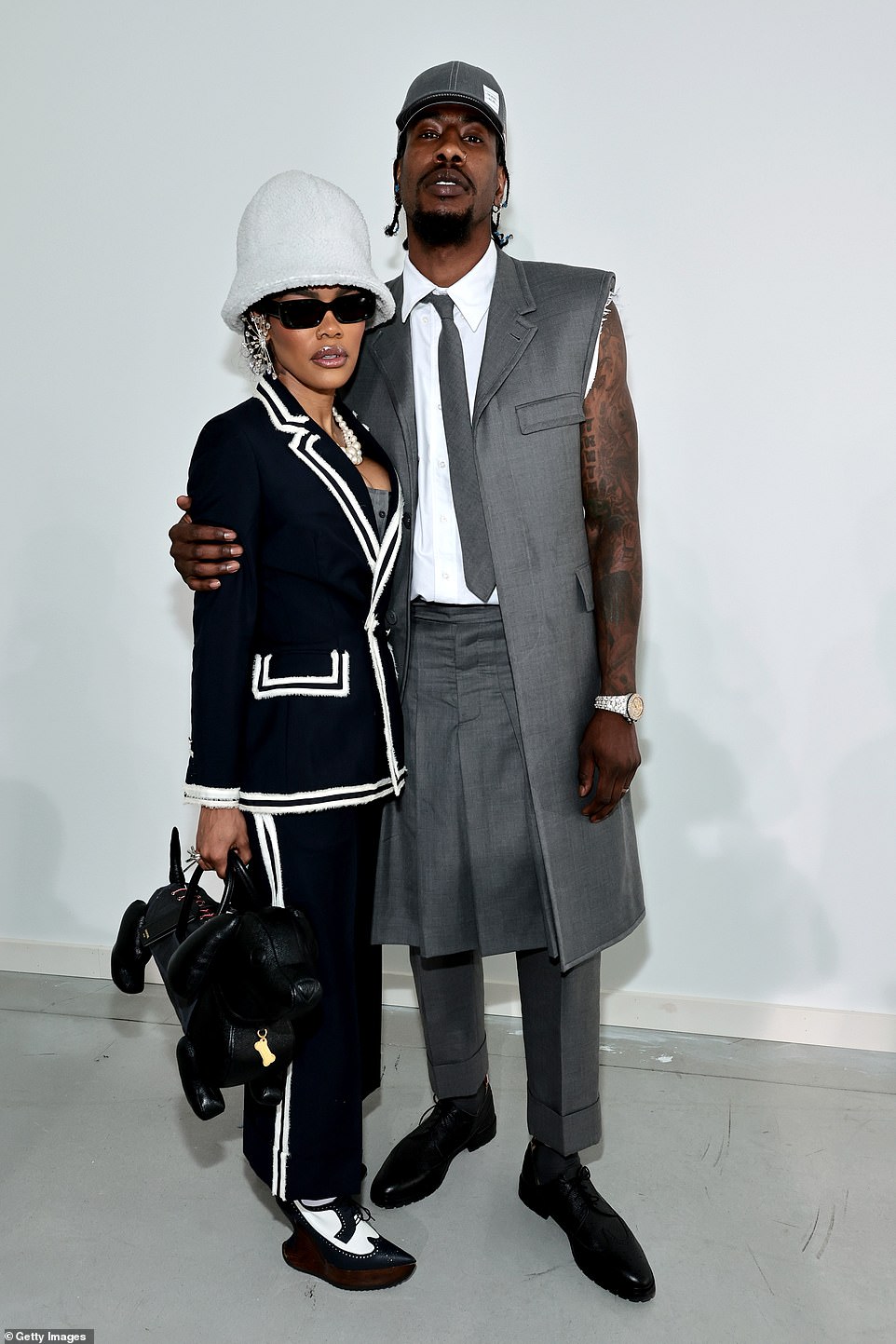 Cute couple: Teyana Taylor looked stylish in a black tweed suit with white trim, along with a black dog-shaped handbag and cool black-and-white saddle shoe–style heels. Her husband Iman Shumpert wore a long gray sleeveless overcoat with a whit shirt, a gray pleated skirt and cuffed trousers underneath