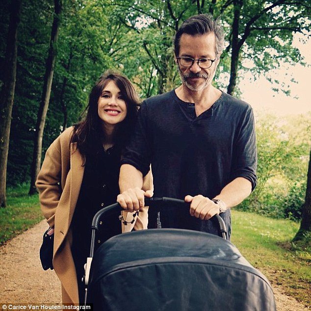 Guy Pearce and Carice Van Houten push a stroller while walking in a park